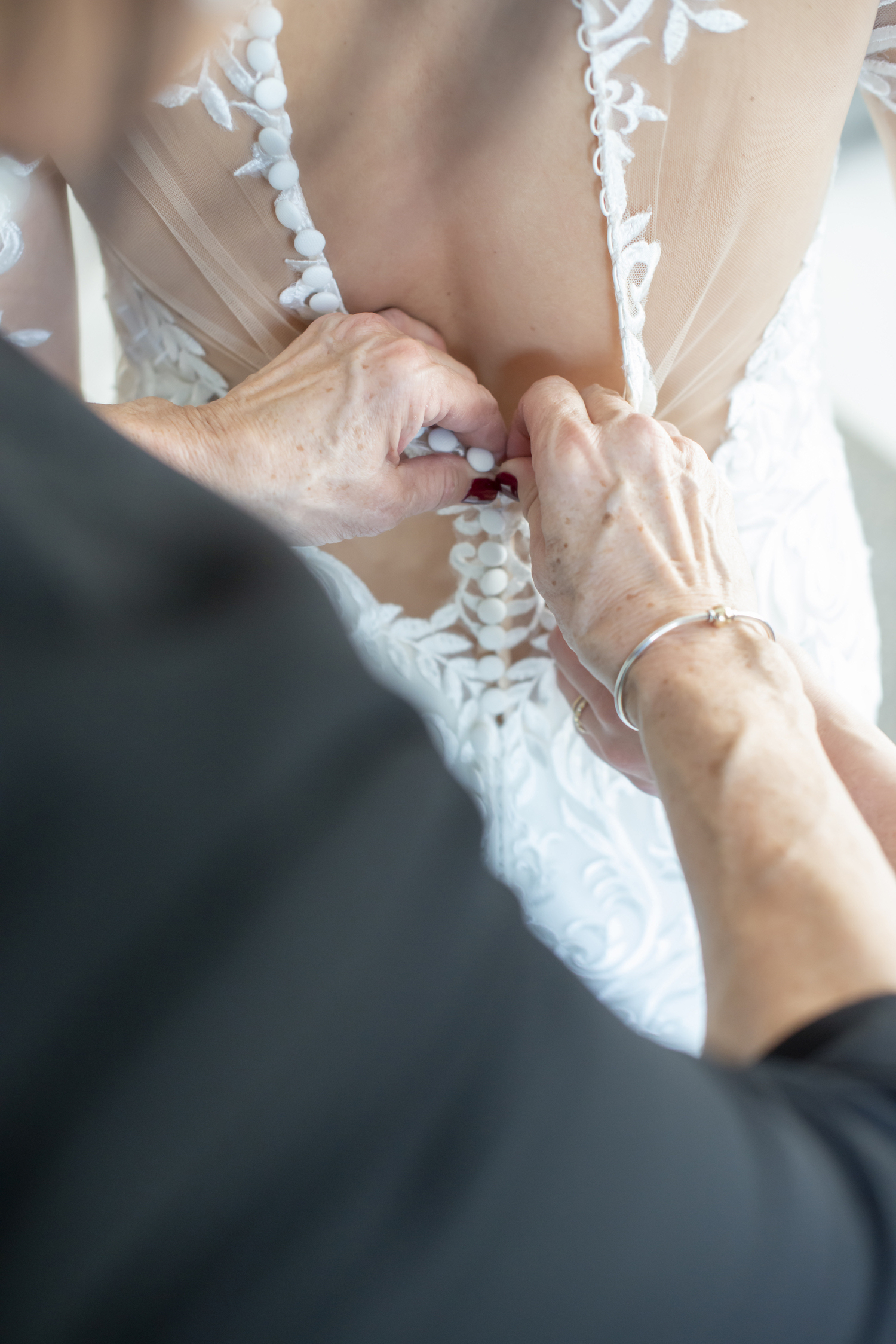 Mother of bride finishing buttoning bride's gown