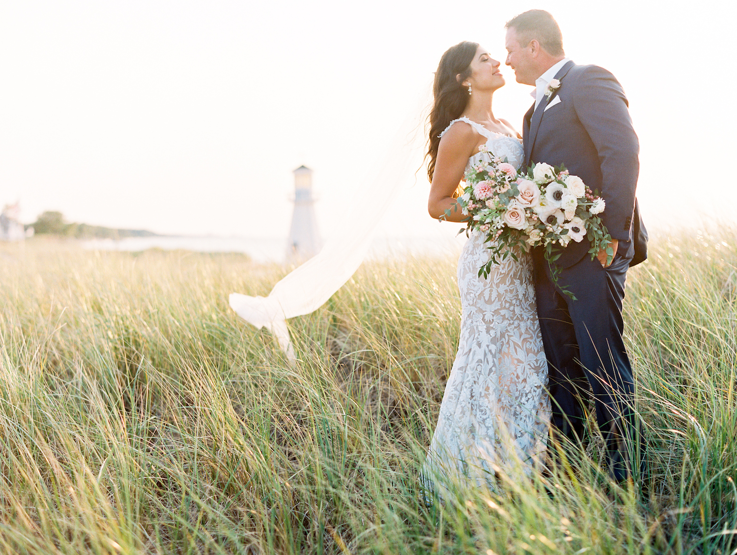Bride and groom smiling with lighthouse in background