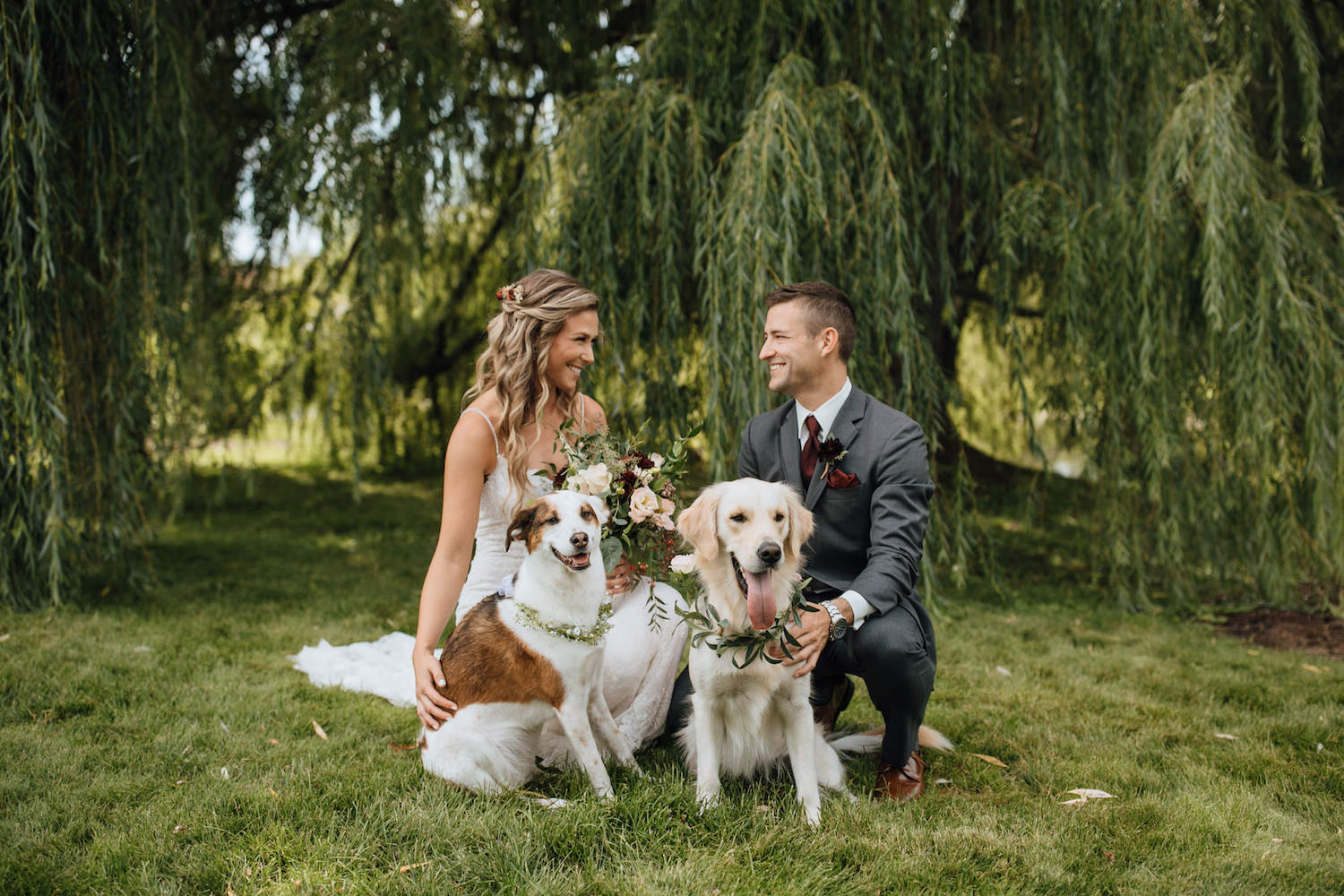 Bride and Groom smiling at each other with dogs