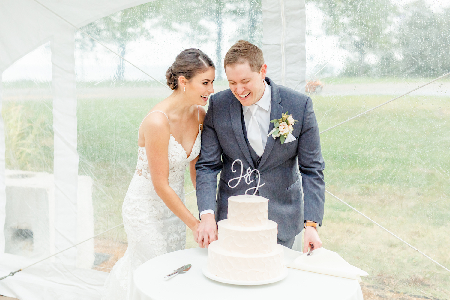 Bride and Groom smiling while cutting their cake