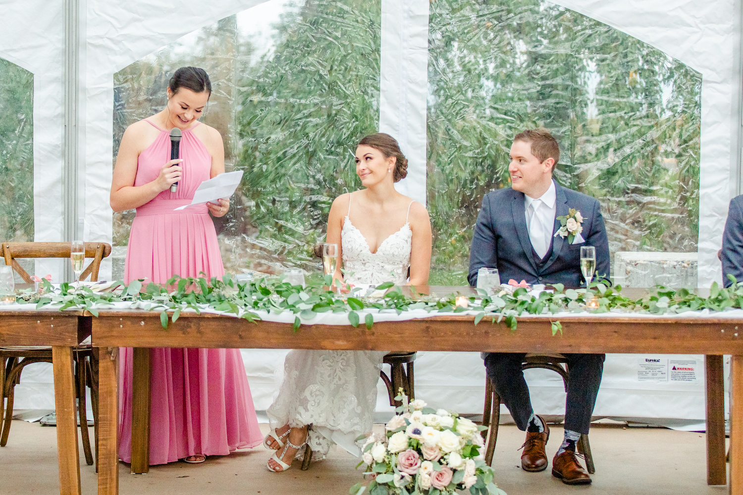 Bride and groom smiling during speeches at the lakehouse wedding reception