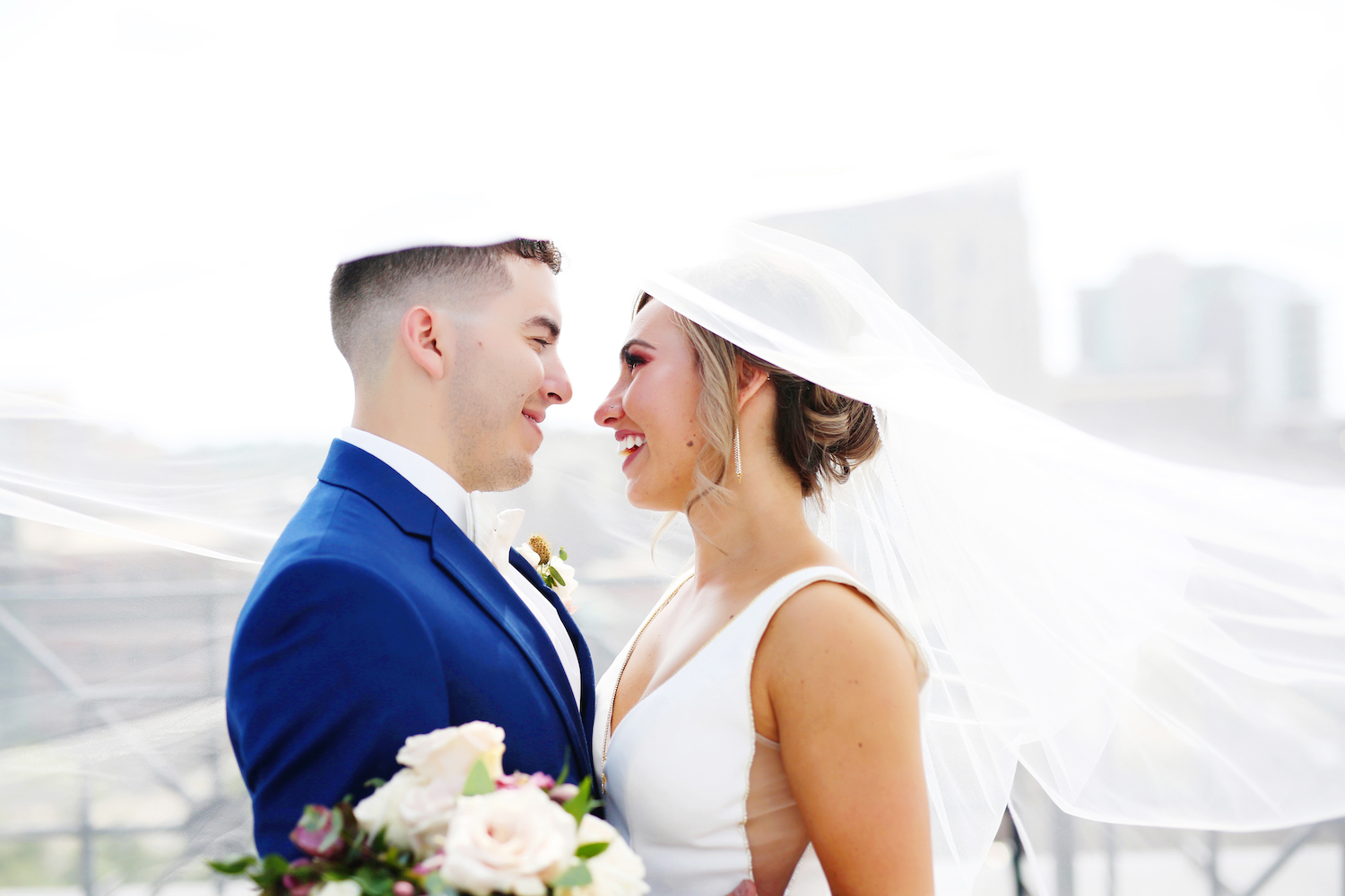 Bride and groom smiling under her veil 