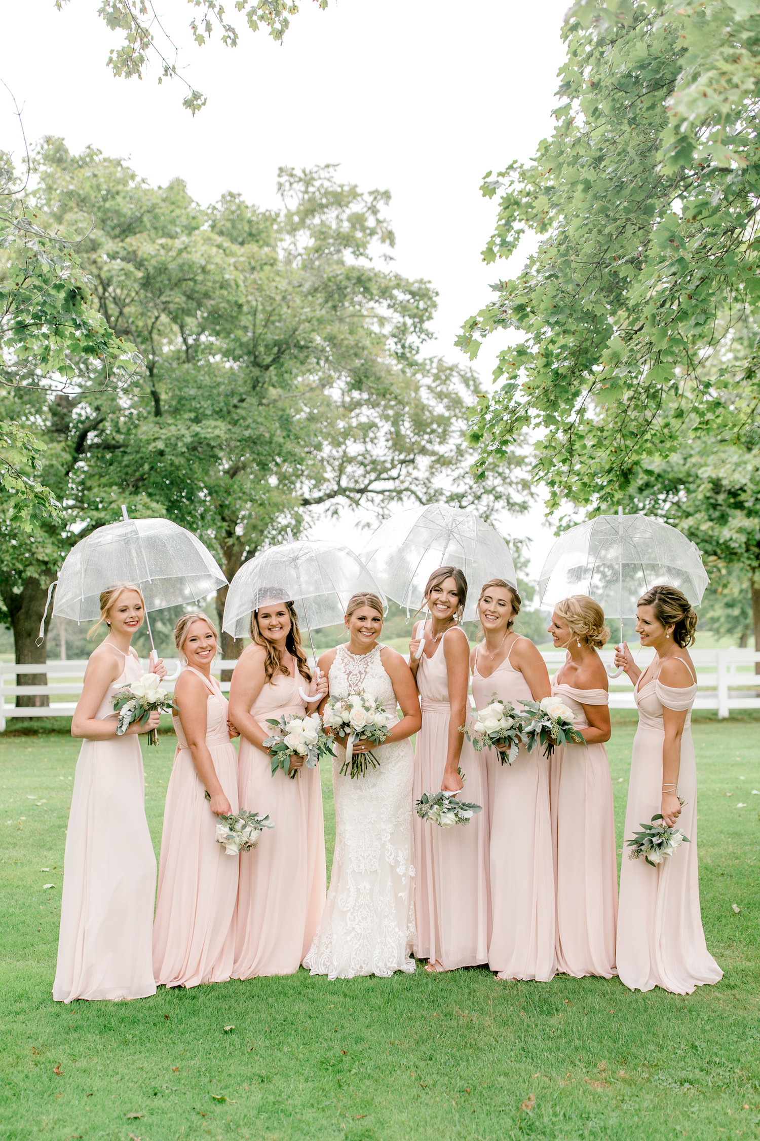 Bride and bridesmaids standing under umbrellas 