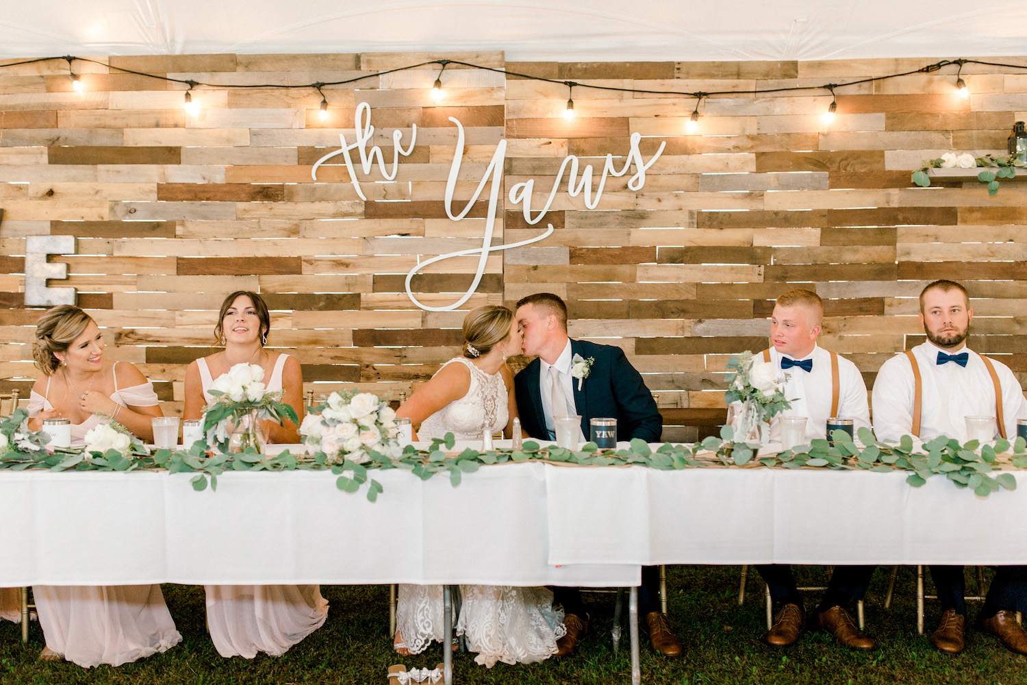 Bride and groom kissing at head table