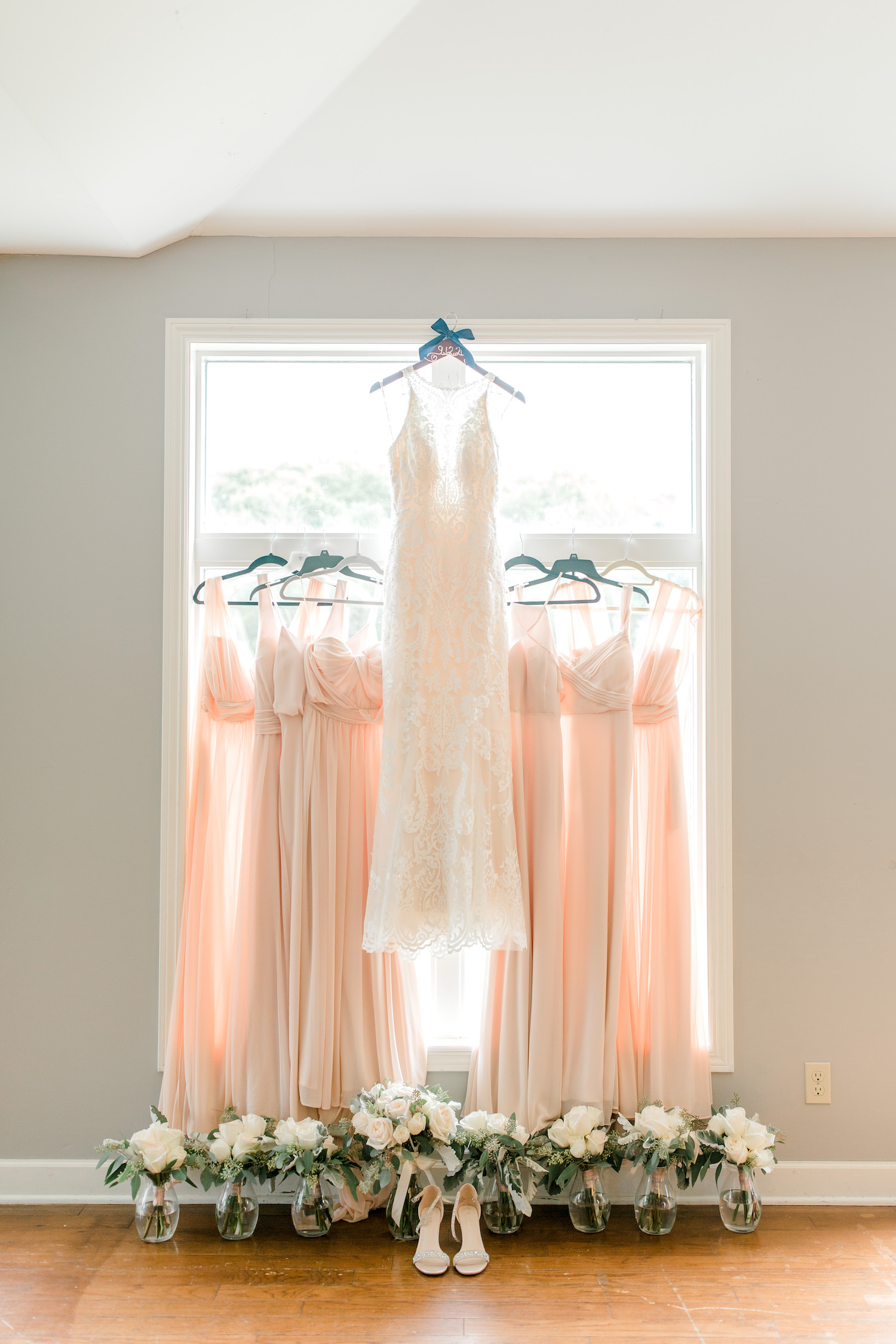 Brides dress hanging with bridesmaids dresses