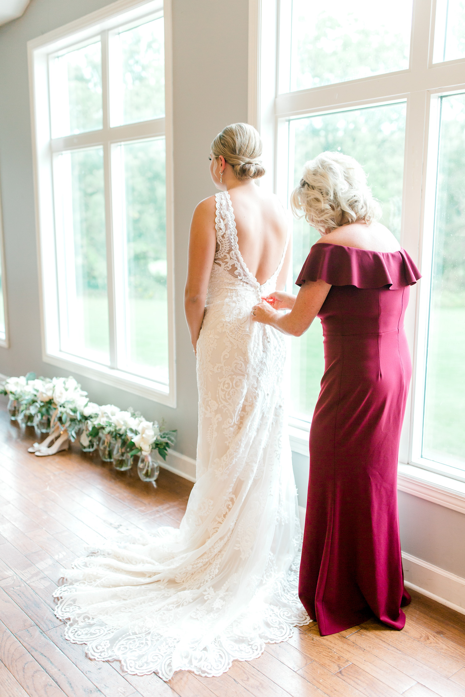 Mother of bride buttoning brides gown