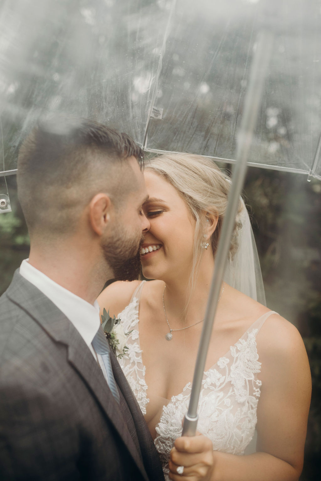 Bride and groom smiling under umbrella 