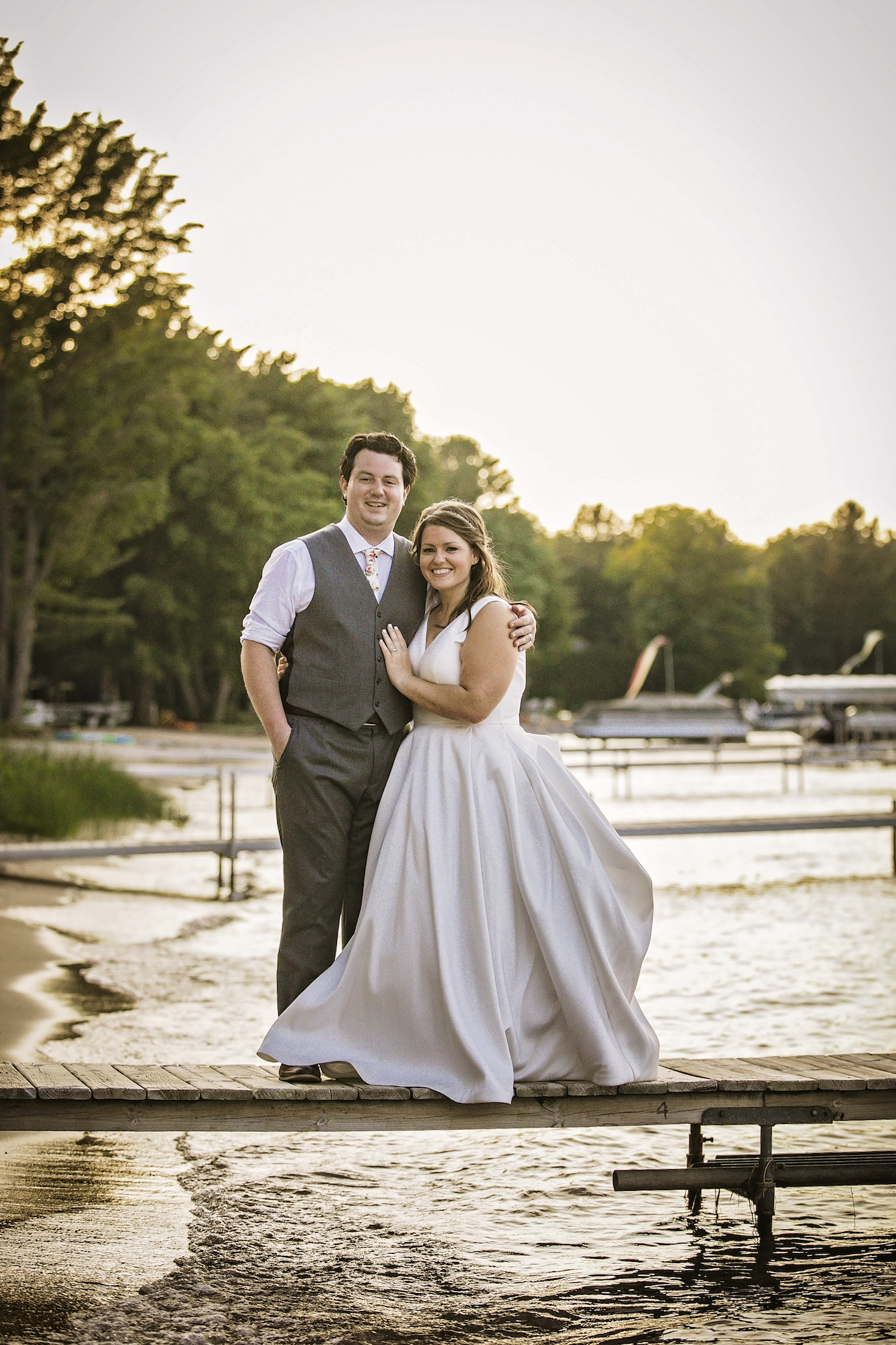 Bride and groom standing on lake dock
