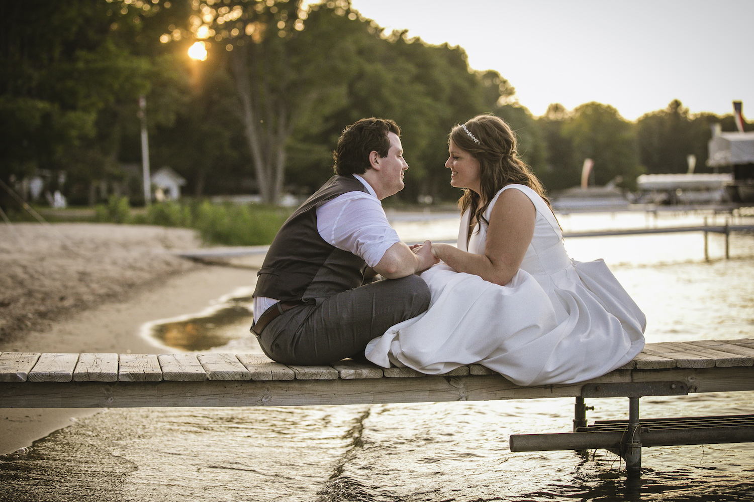 Bride and groom sitting on dock at Higgins Lake wedding