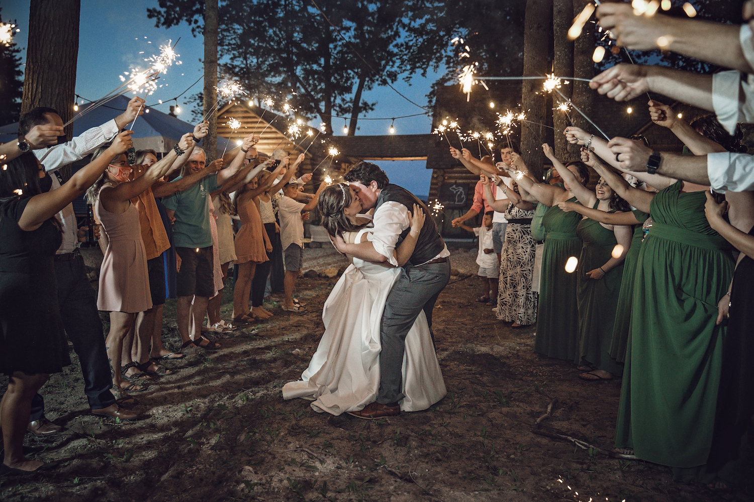 Groom dipping bride and kissing her under sparklers