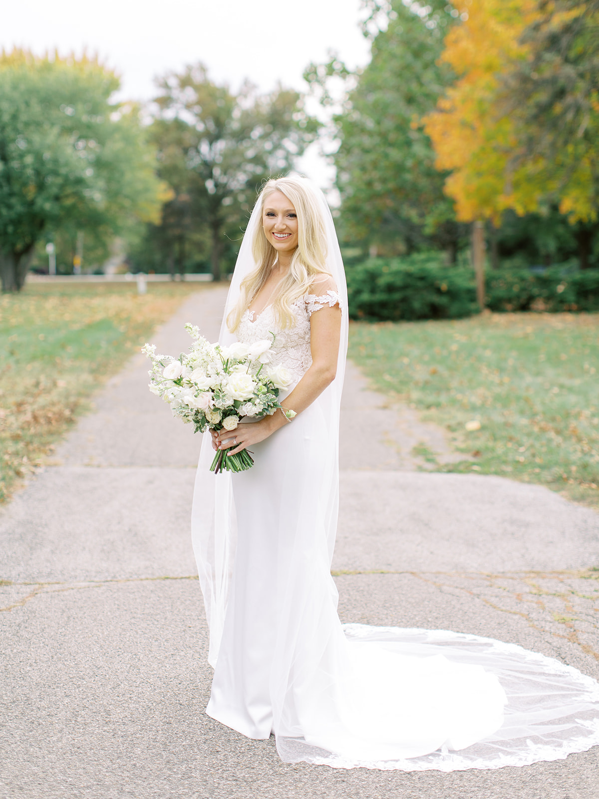 Bride standing in driveway with bouquet before Ritz Charles wedding
