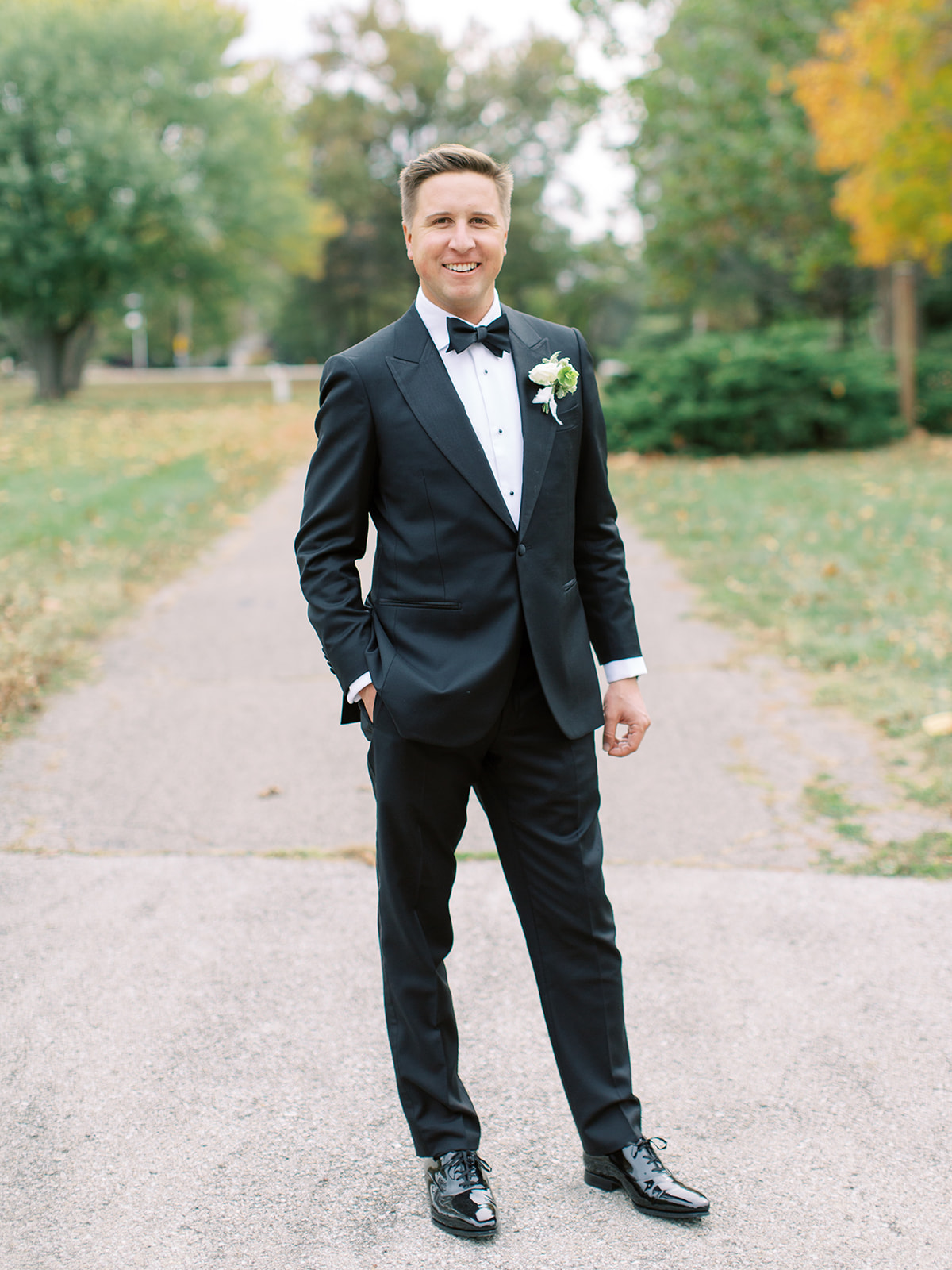 Groom standing in driveway smiling before Ritz Charles wedding