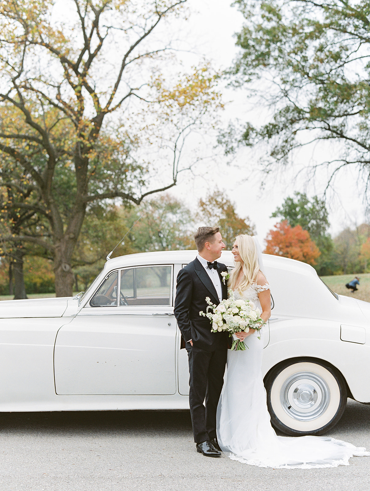 Bride and groom looking at each other in front of classic car