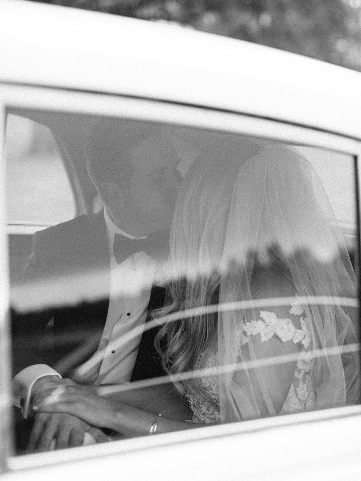 Bride and groom kissing inside of car