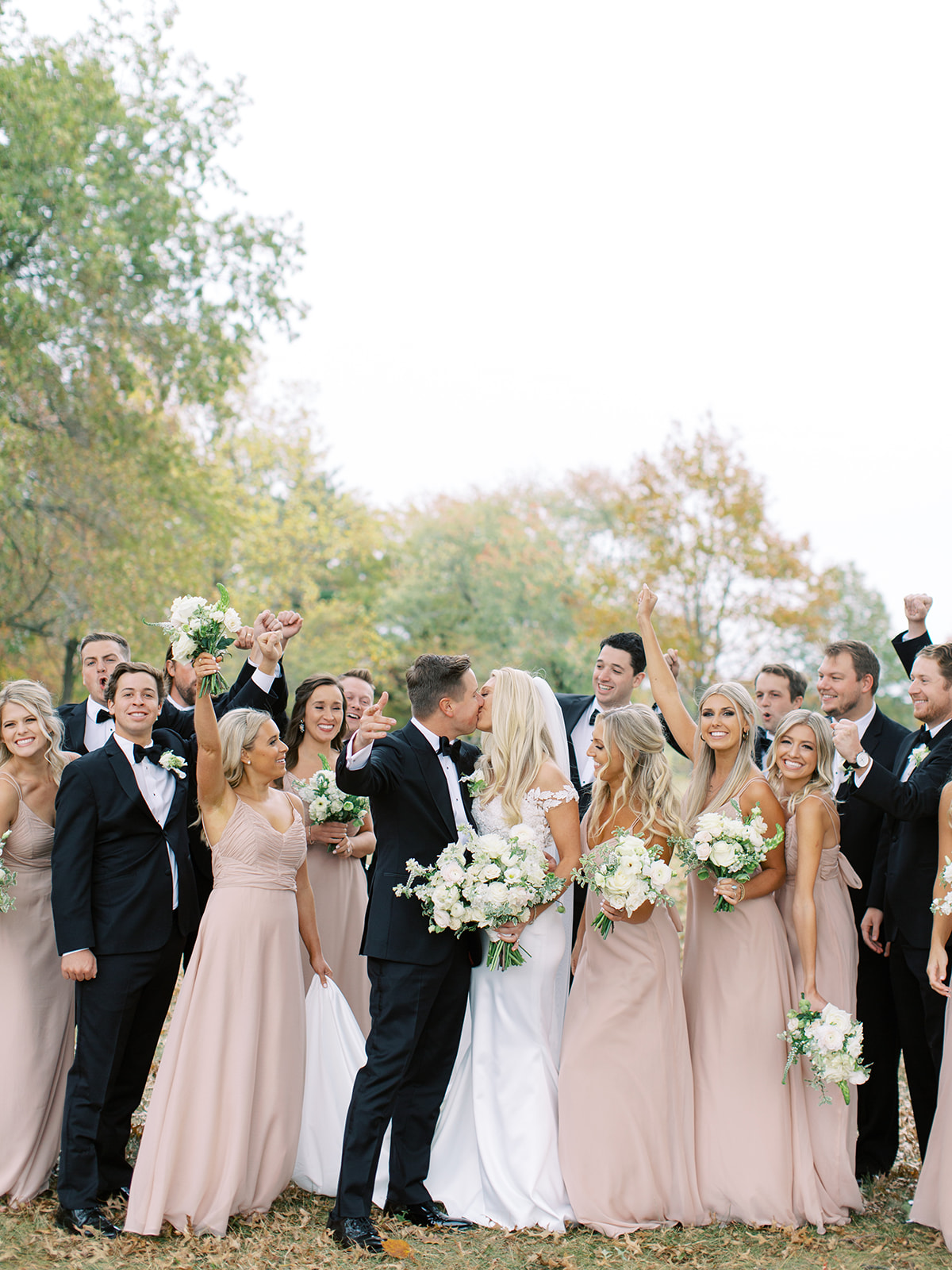 Bridal party cheering on bride and groom kissing