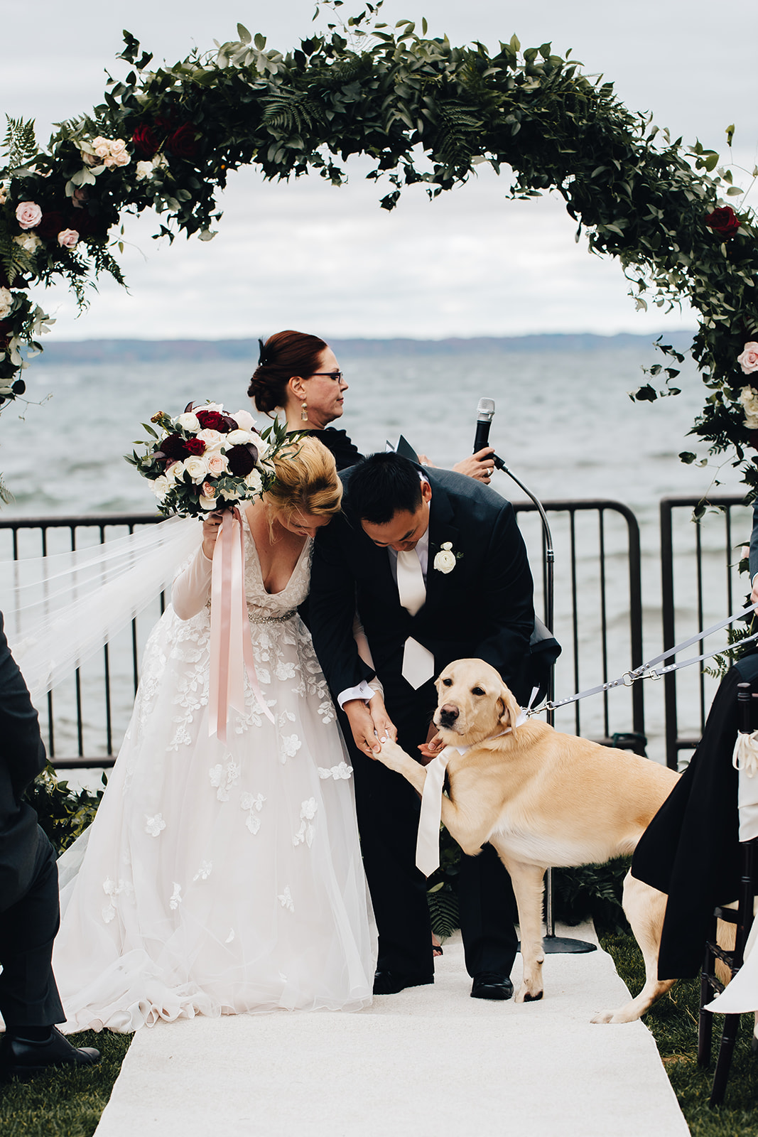Bride and groom smiling at their dog at alter