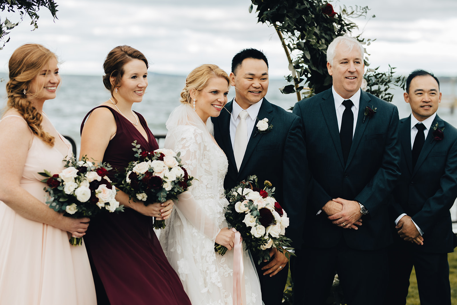 Bridal party smiling together by water