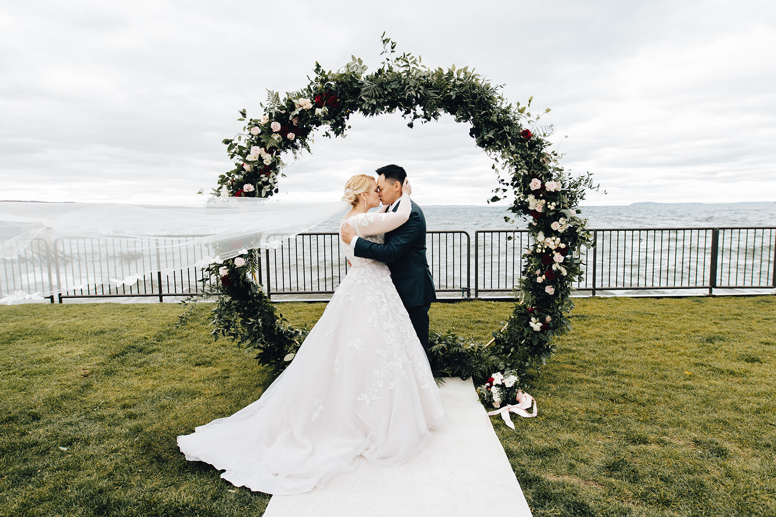 Bride and groom kissing by water of West Bay Beach wedding