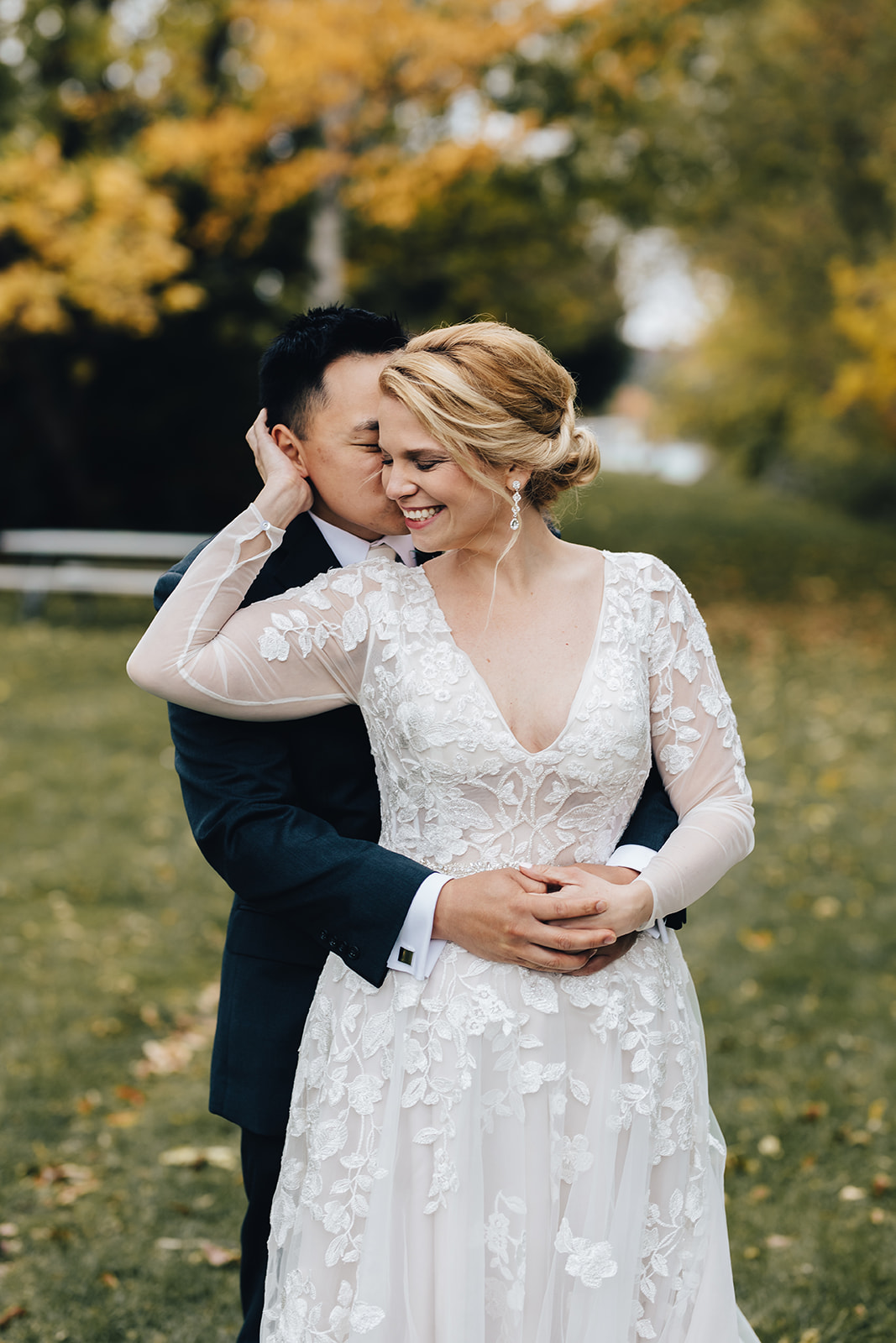 Groom holding his bride from behind while she smiles