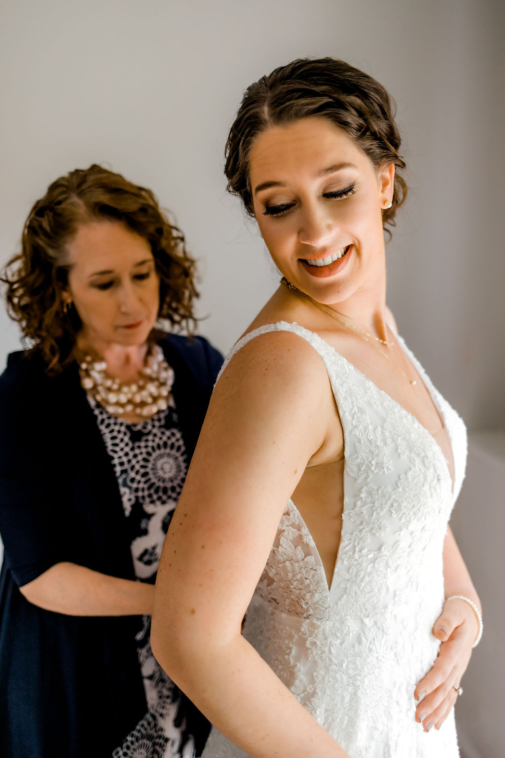 Mother of bride buttoning brides wedding gown before Jackson, MI wedding