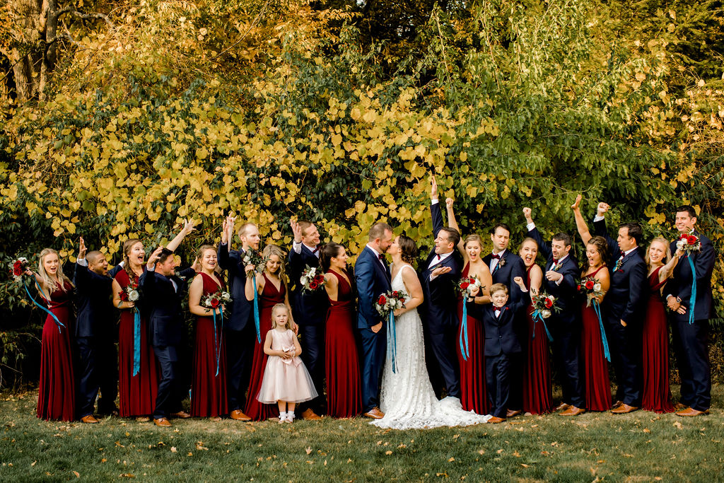 Bridal party cheering at bride and groom kissing