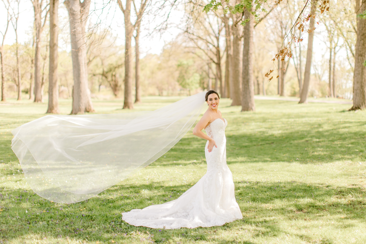 Bride smiling with her veil flowing behind her