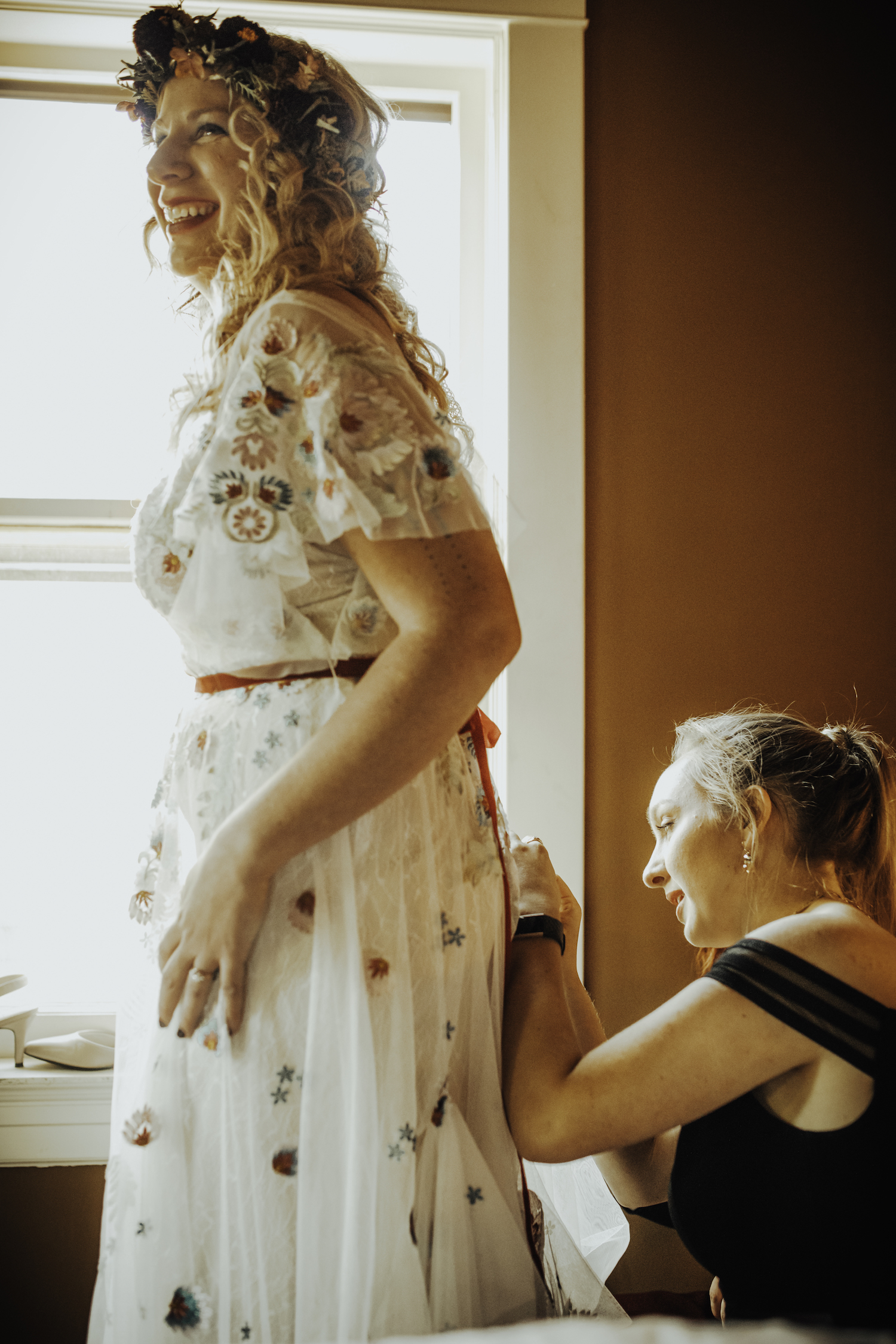 Bride smiling while her dress is buttoned