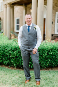 Groom smiling outside the felt mansion on his wedding day