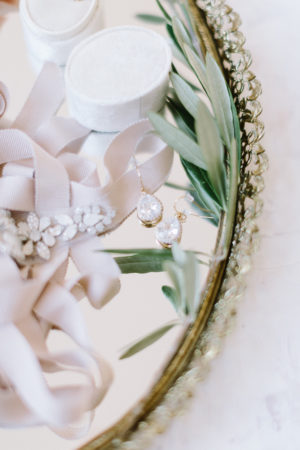 Wedding dress belt and earrings laying on a gold tray