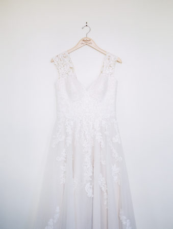 A wedding gown hanging up on a wood hanger