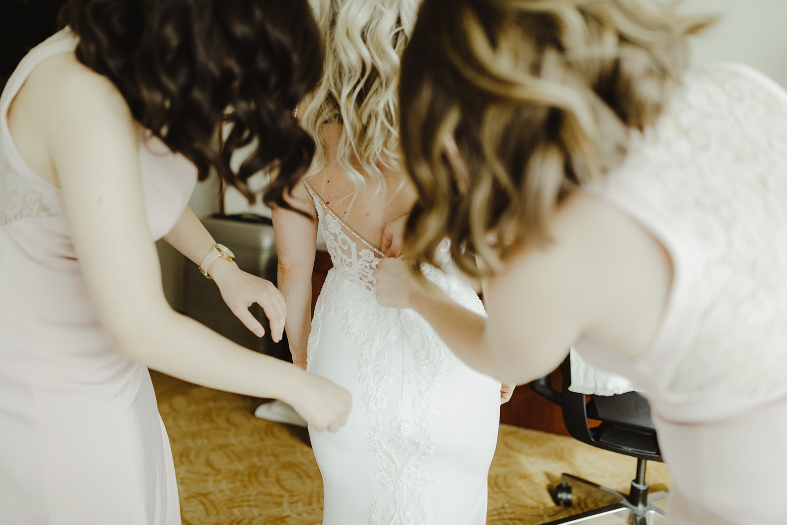 Bridesmaids zipping up a brides dress