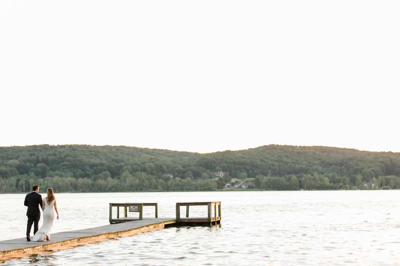 A couple walking on the dock during their Boyne Mountain Resort wedding at Deer Lake
