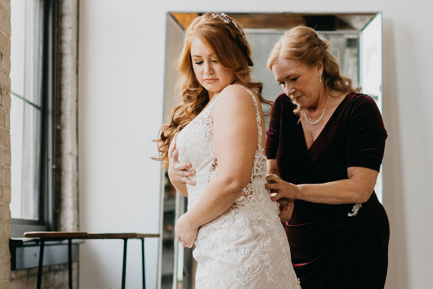 Mother of bride buttoning her wedding dress